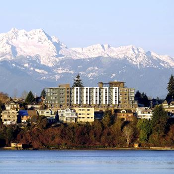 A large building sits in front of a snowy mountain range  at Spyglass Hill Apartments, Bremerton, 98337